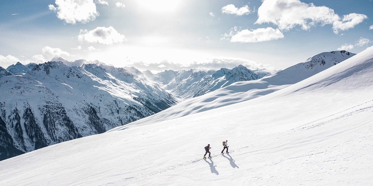 2 people enjoying a winter hike on a snow covered mountain.